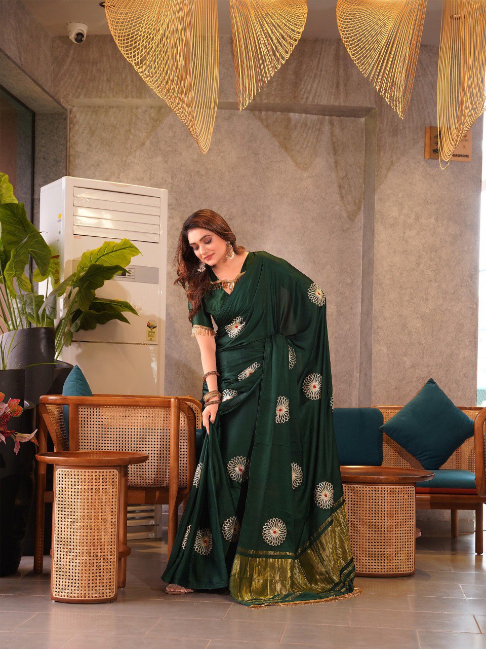 Model wearing a dark green Gaji Silk Jaipuri Saree with white floral Gota Patti work and gold border, draped elegantly.