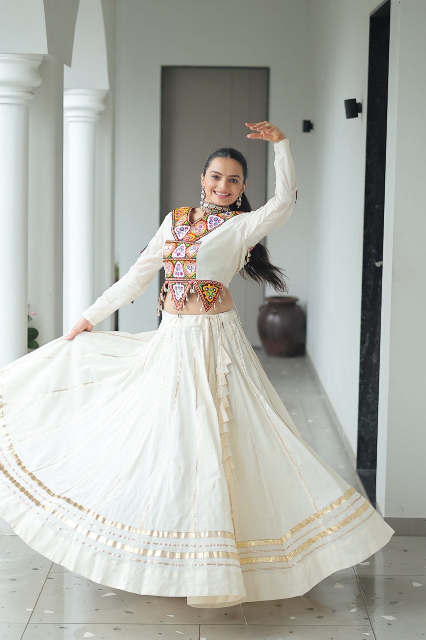 Woman in white Kora Cotton Lehenga Choli with colorful embroidered top, dancing with a flared skirt.