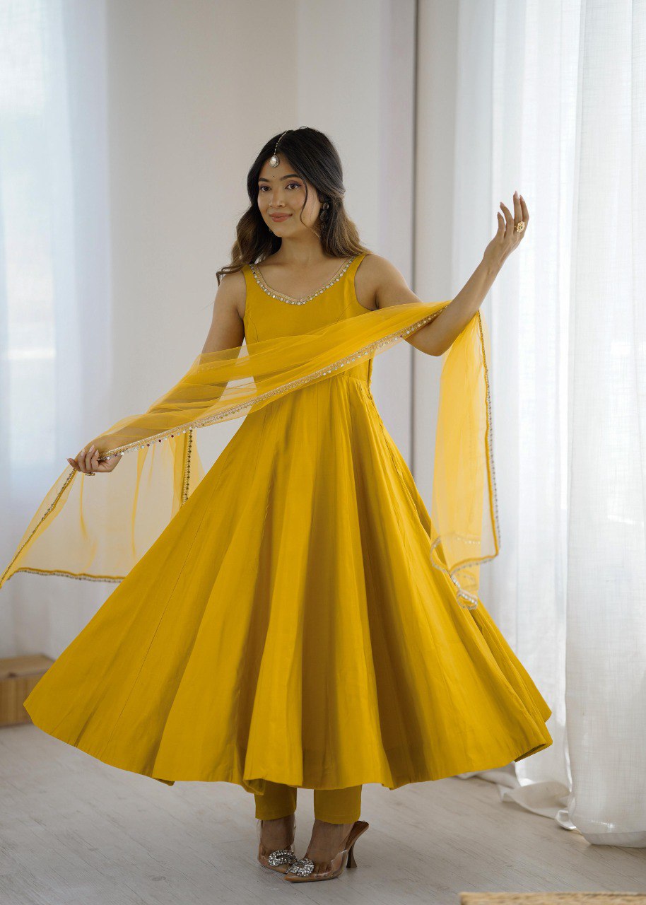 Woman wearing a vibrant yellow Anarkali suit with a flowing flare and dupatta, styled for a festive occasion.
