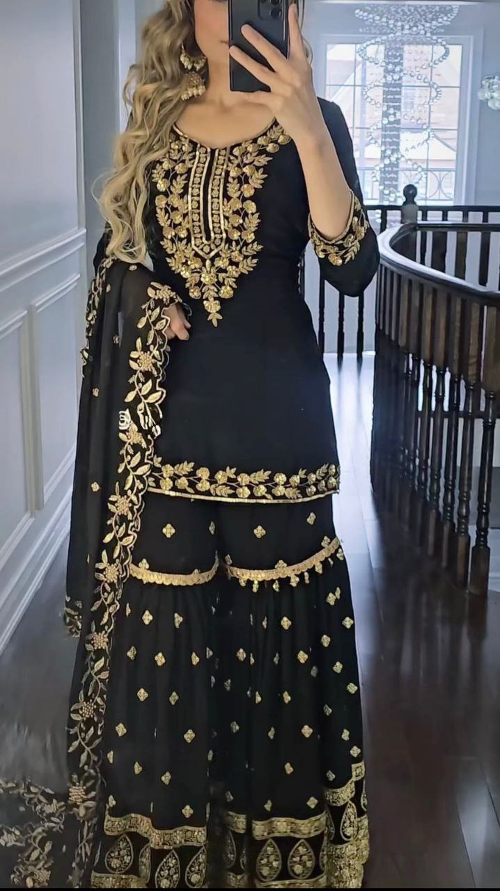 Model wearing a black georgette sharara suit with intricate gold embroidery and sequins.