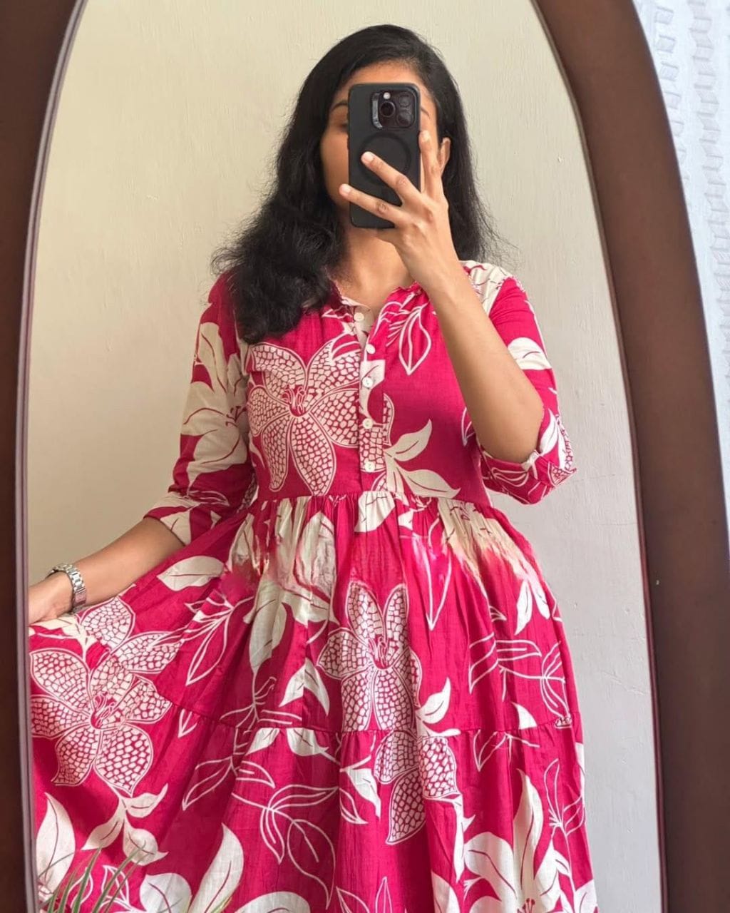 Woman wearing a pink and white floral print Ruzana Maxi Dress by TRENDBUY, showing the tiered skirt and button detail.