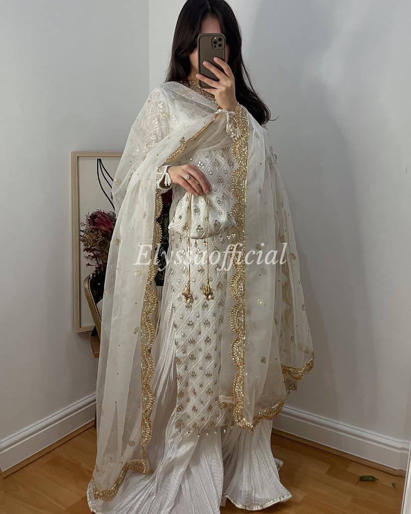 TRENDBUY model wearing elegant white Fox Georgette palazzo suit with gold mirror work dupatta.