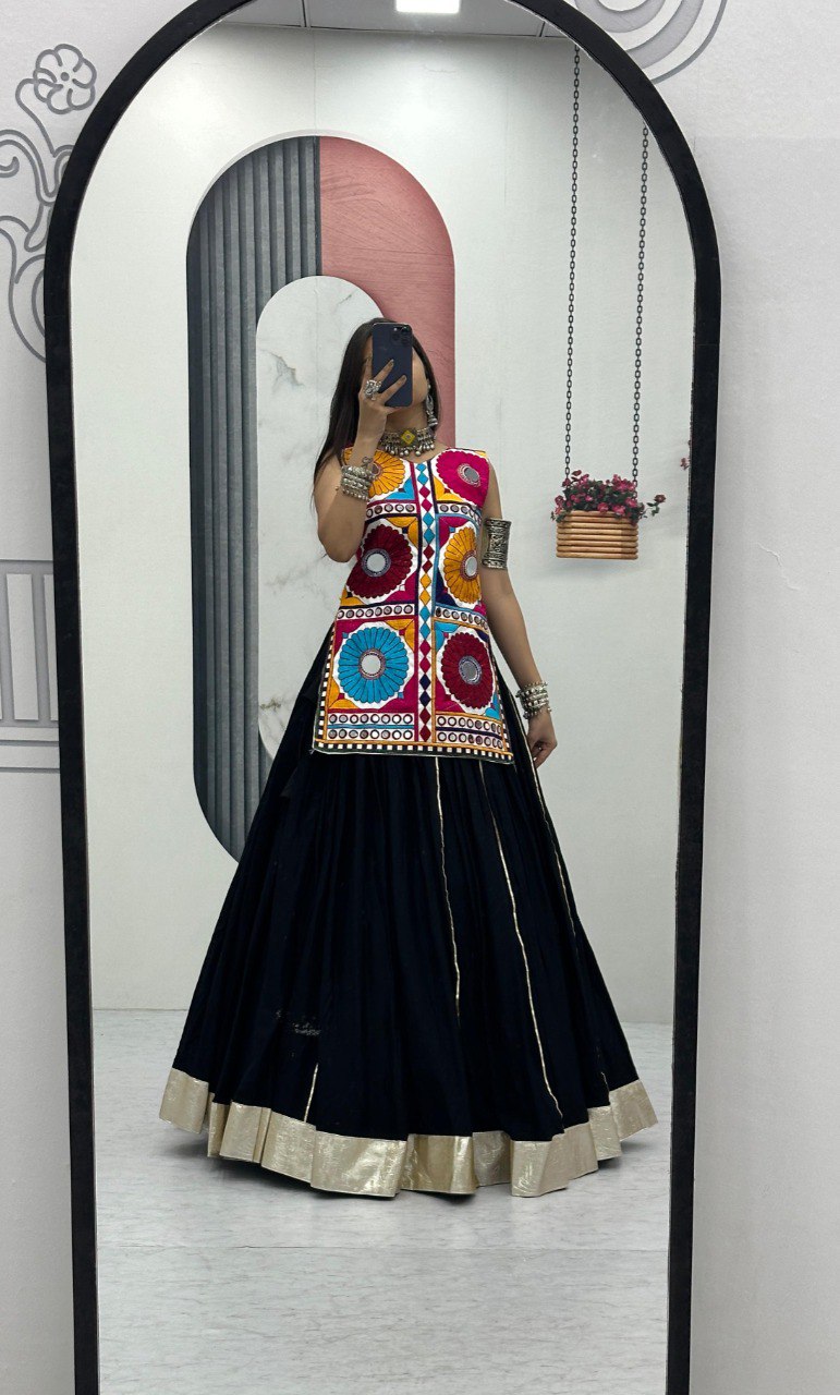 Model in Navratri special Kediyu Lehenga with black skirt and colorful mirror work top, posing in a mirror.