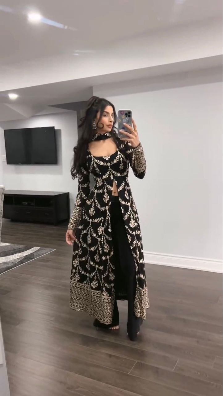 Woman wearing a black embroidered and sequined long kurta with flared sleeves and matching black pants, posing for a mirror selfie.