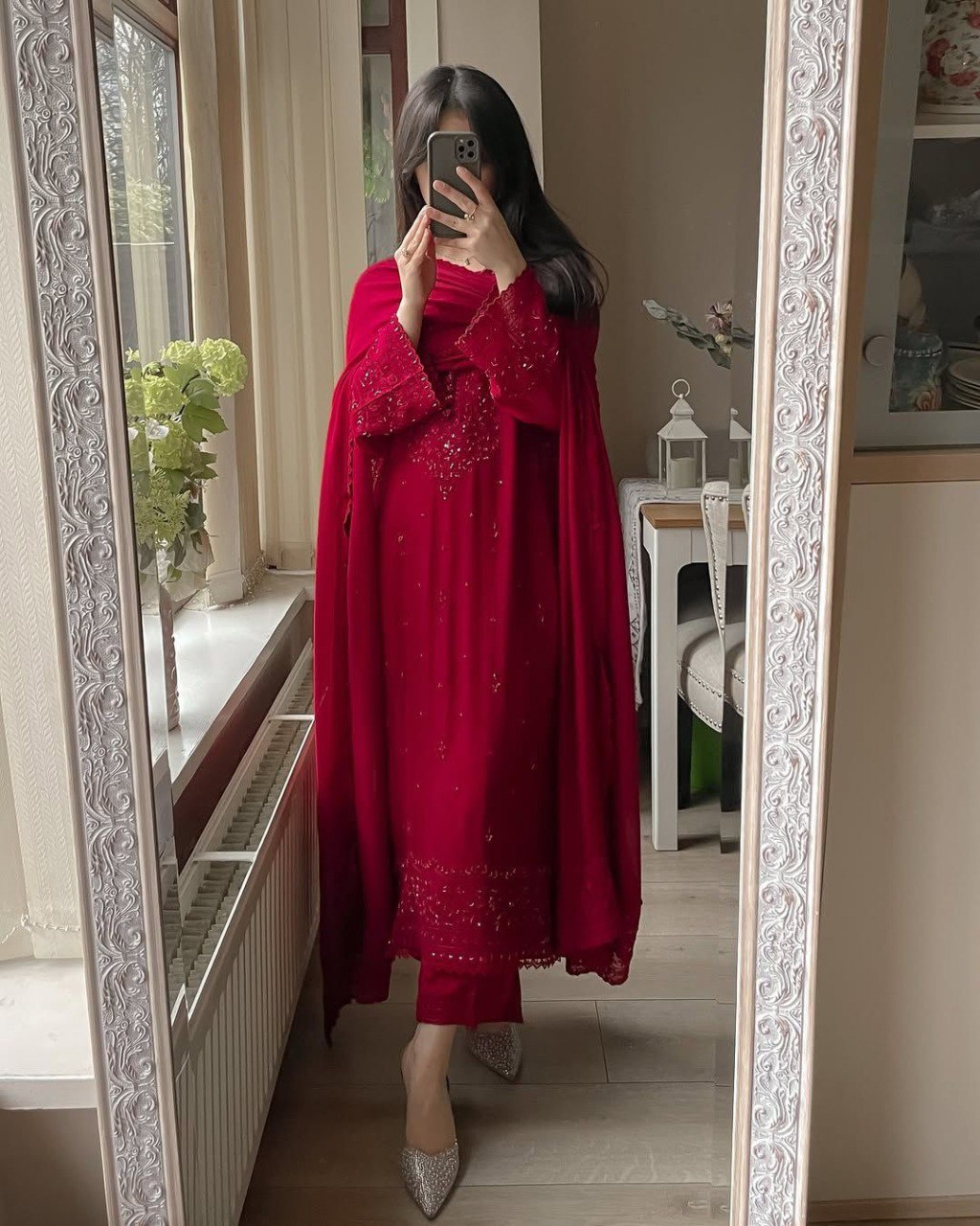 Full-length shot of a woman in a red georgette plazzo suit with sequence embroidery, reflected in a mirror.
