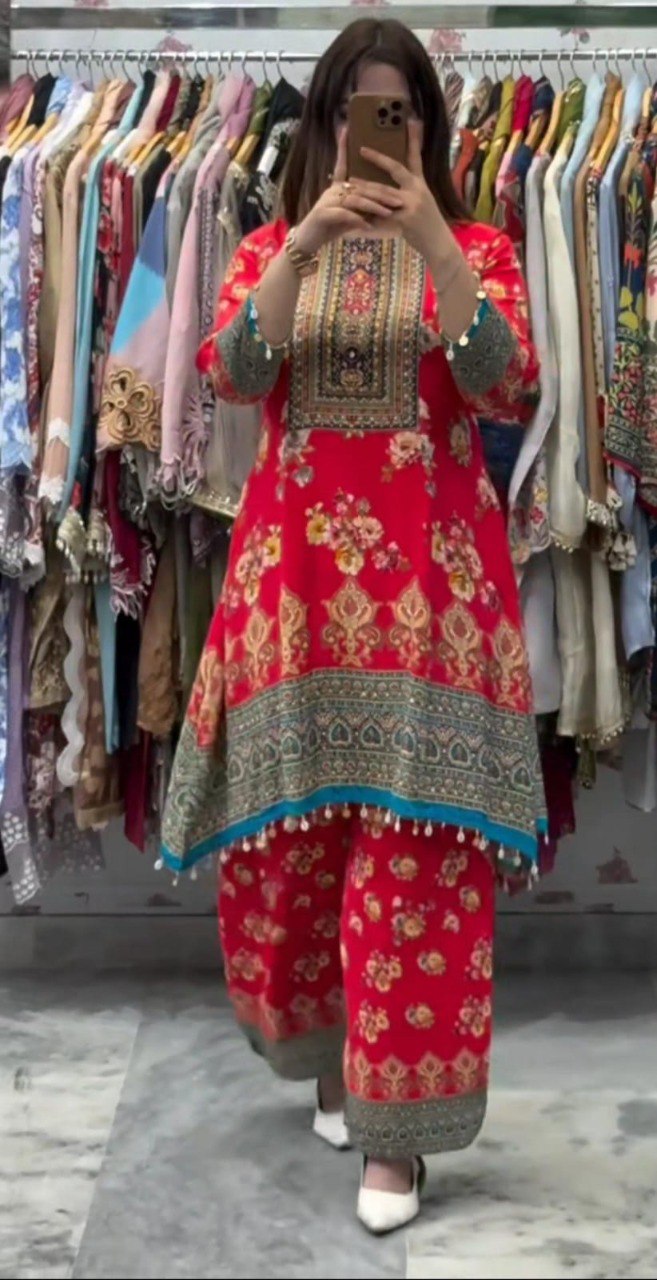 Full shot of a model wearing the red malai satin co-ord set with digital prints and mirror work, standing in front of a clothing rack.