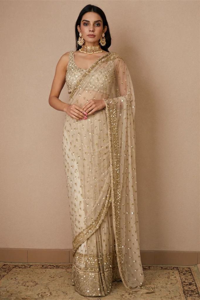 Model wearing a cream butterfly net designer saree with gold embroidery and sequins, paired with a choker necklace.