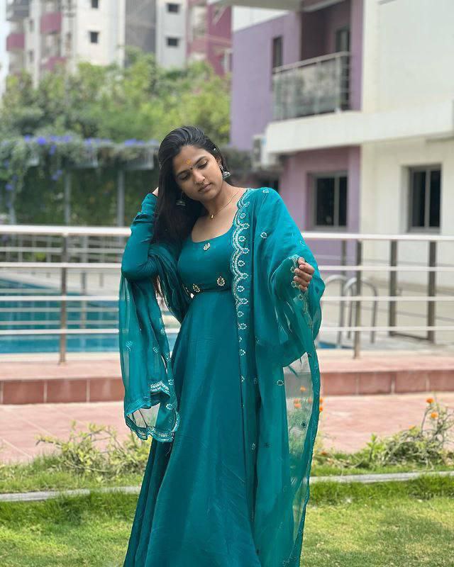 Model posing outdoors in a teal blue Anarkali gown with a matching dupatta, showing off the flowing skirt and sleeve details.