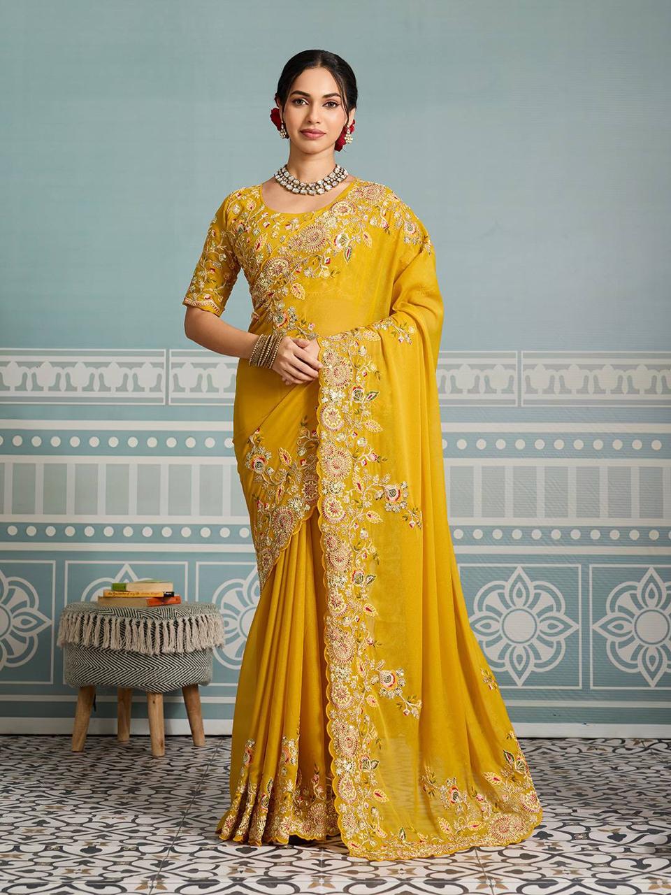 Full-length shot of a model elegantly posing in a mustard yellow georgette saree with intricate floral embroidery and cutwork border.