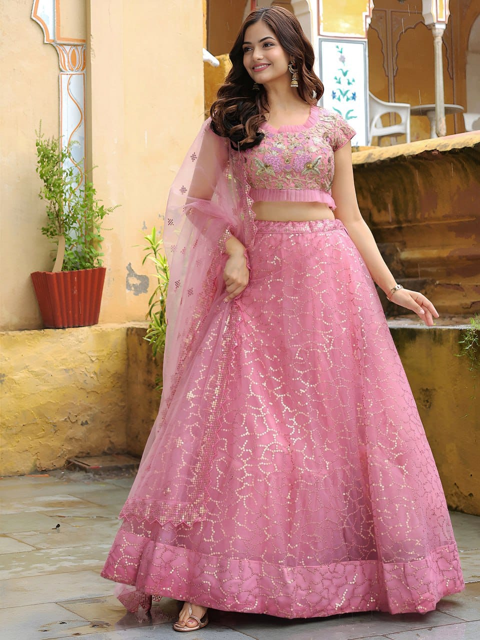 Close-up of intricate golden zari and sequin floral embroidery on soft pink net fabric