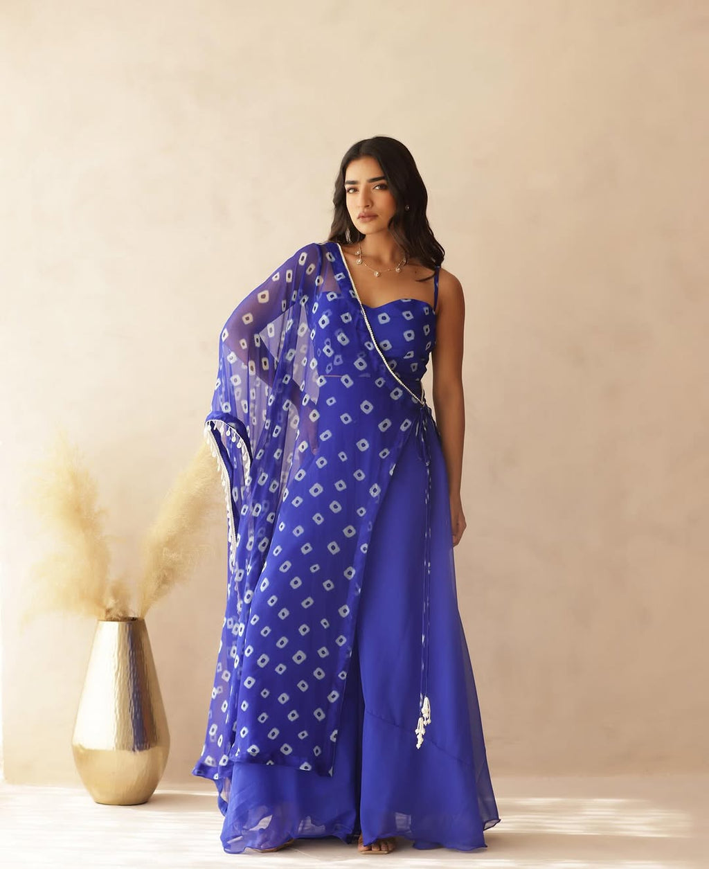 Woman posing gracefully in a vibrant blue Fox Georgette fusion Palazzo set with a printed Bandhani dupatta.