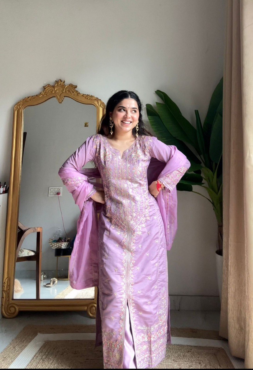 Woman posing elegantly in a light purple Roman Silk kurti set with sequence embroidery, smiling, in front of a mirror.