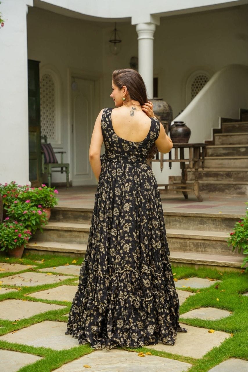 Back view of model posing in black floral Fox Georgette maxi dress with elegant tiered flare.