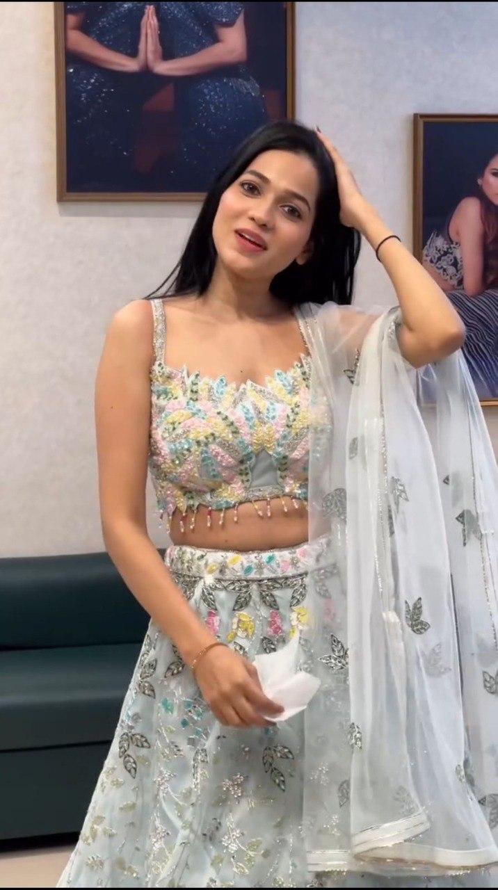 Model showcasing front view of light blue organza sequins embroidery lehenga choli set, smiling.