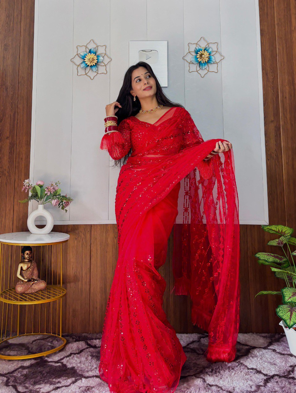 TRENDBUY model posing elegantly in a dazzling red sequin net saree and matching long-sleeve blouse, looking up.