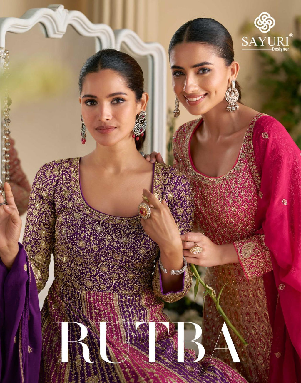 Two models showcasing Sayuri Designer Rutba gowns, one in purple-pink and one in pink-orange, with heavy gold embroidery.