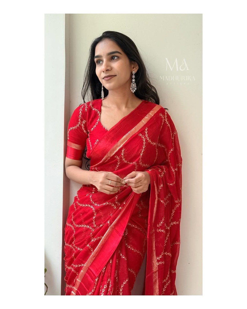 Woman in elegant red Tibby silk saree with sequin work and traditional earrings, posing gracefully