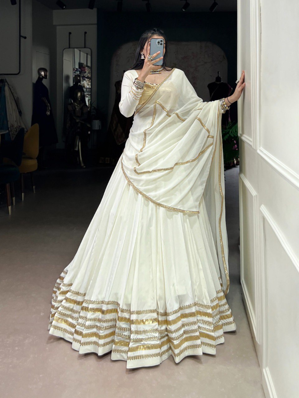 Elegant woman posing in a white and gold full-flair Rayon Lehenga Choli set, perfect for Navratri.