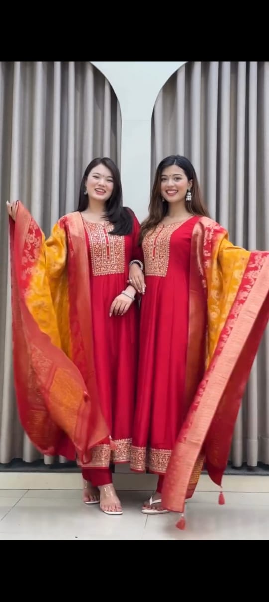 Two models showcasing the TRENDBUY Red Anarkali kurti set with vibrant red and yellow Banarasi silk dupattas.
