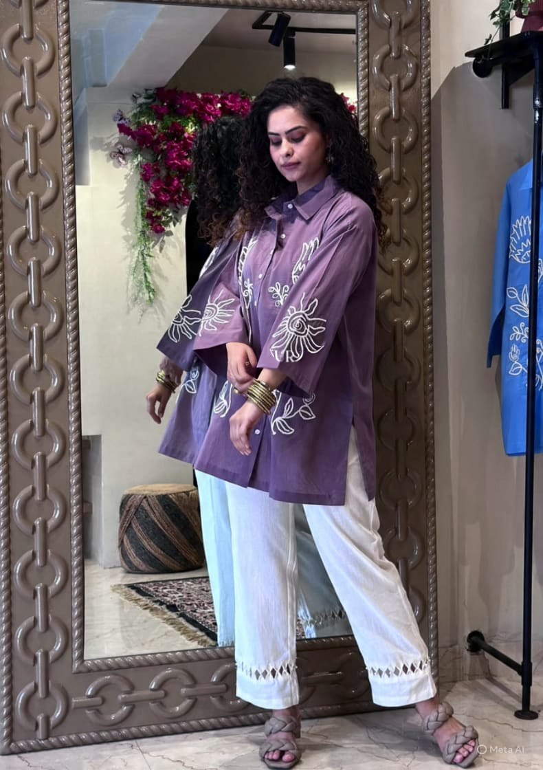 TRENDBUY model in purple embroidered cotton tunic and white pants, looking stylish by a mirror