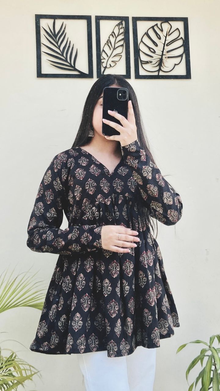 TRENDBUY model wearing a black geometric patterned long-sleeve cotton peplum top with white pants.