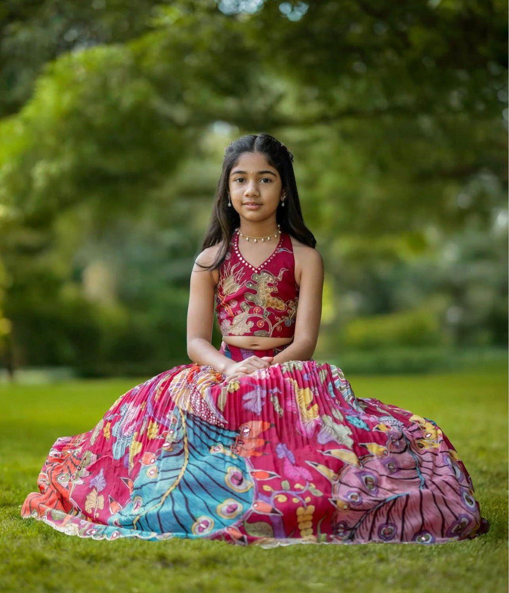 Young girl modeling a vibrant fuchsia pink and multi-color printed crepe lehenga choli set outdoors on grass.