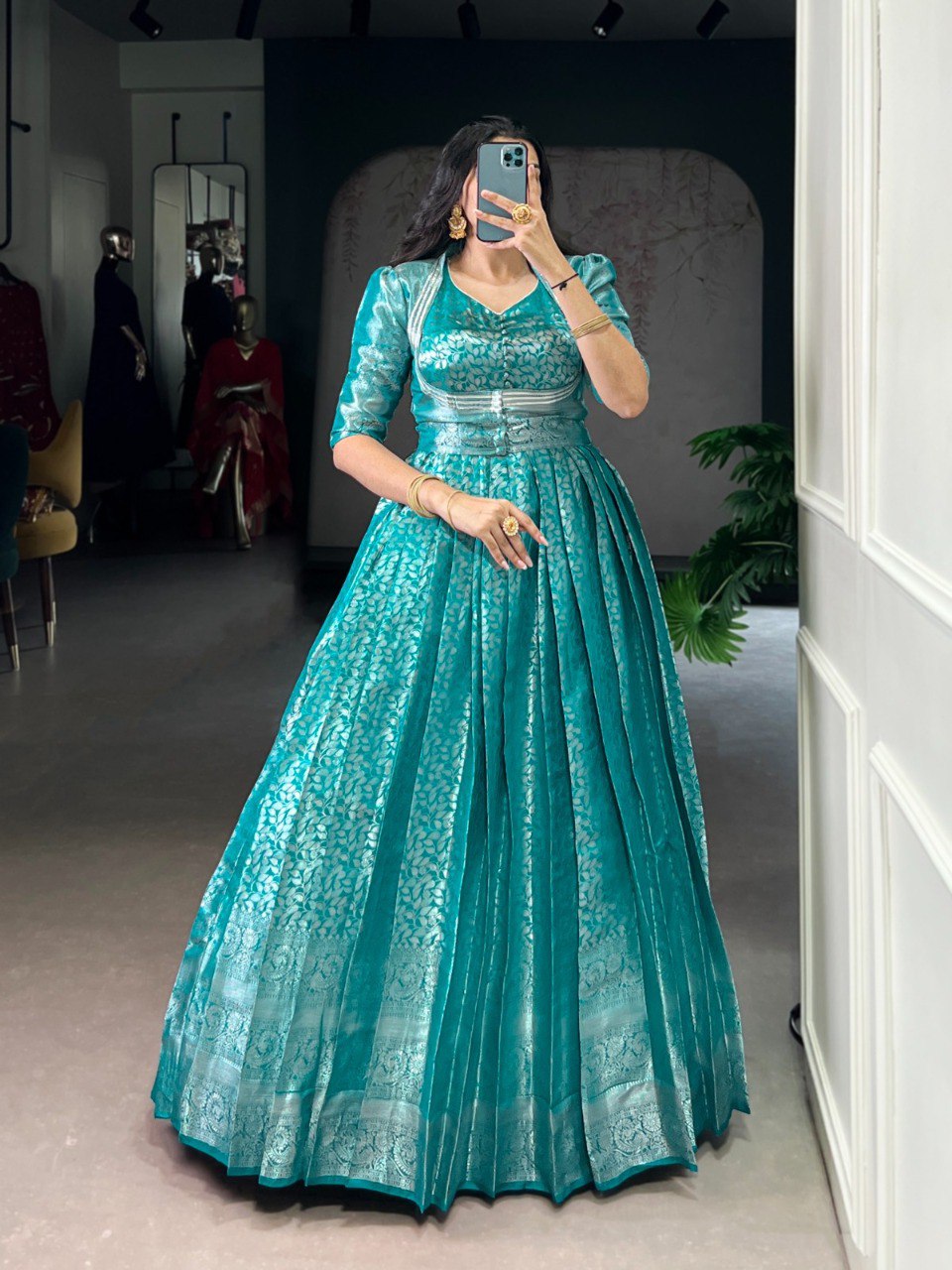 Elegant woman showcasing a teal Kanjivaram zari weaving gown with a matching koti jacket, front view.
