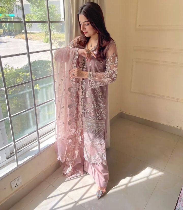 Dusty Pink Heavy Net Sharara Suit with intricate sequence and pearl work, modeled by a woman near a window.