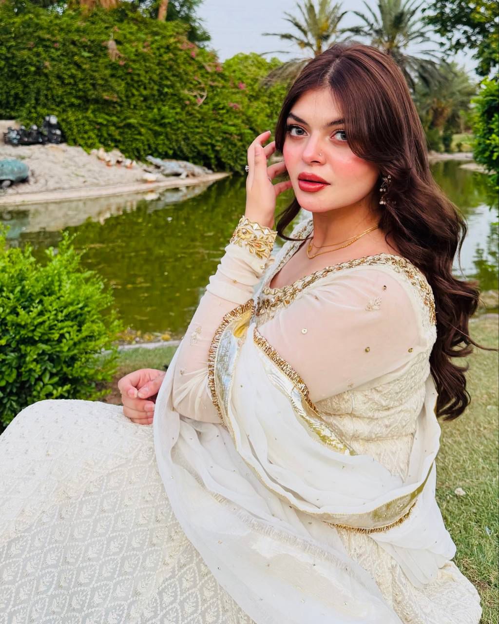 Off-white designer georgette gown set with embroidery and mirror work, worn by a model in a garden, close-up