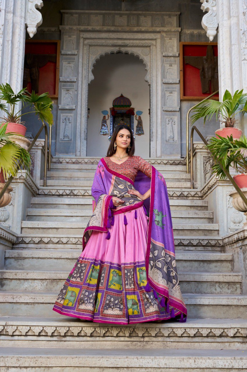 Model in vibrant pink Tasar silk lehenga with purple kalamkari dupatta and maroon blouse, posing on grand palace stairs.