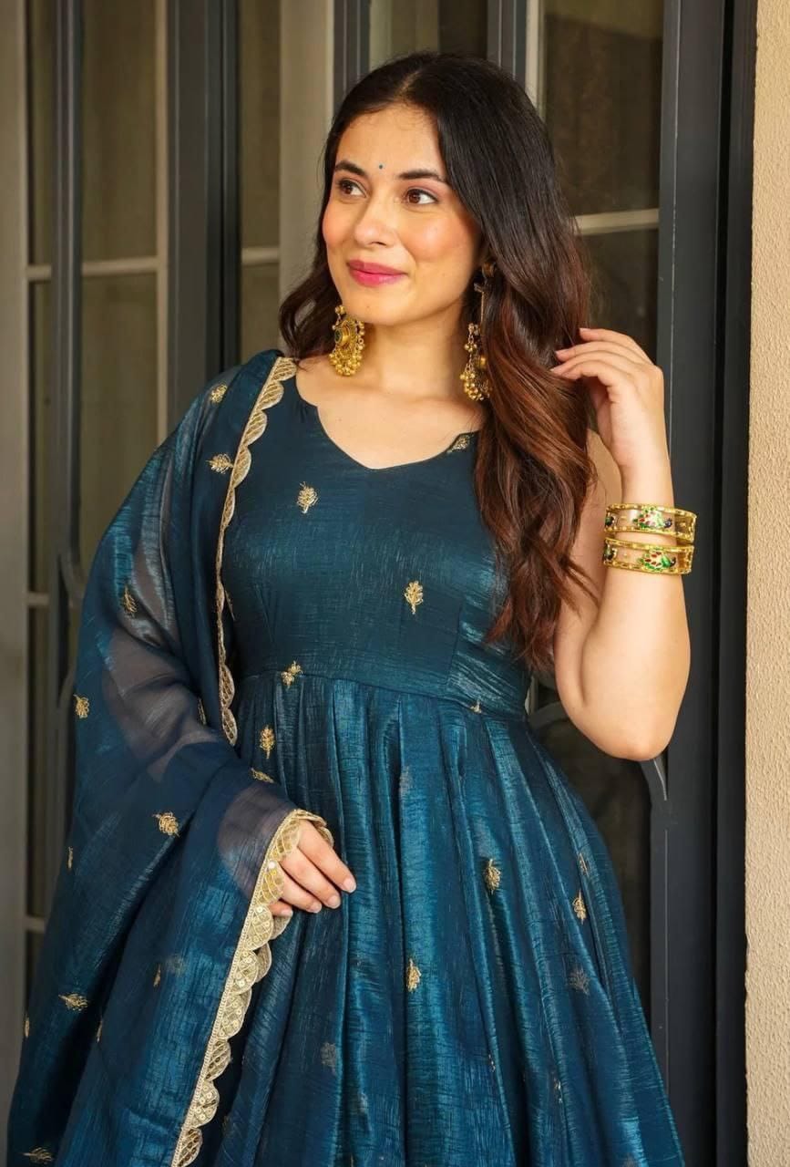 Smiling woman in teal blue Gold Crazy sharara suit, looking right, with bangles and earrings.