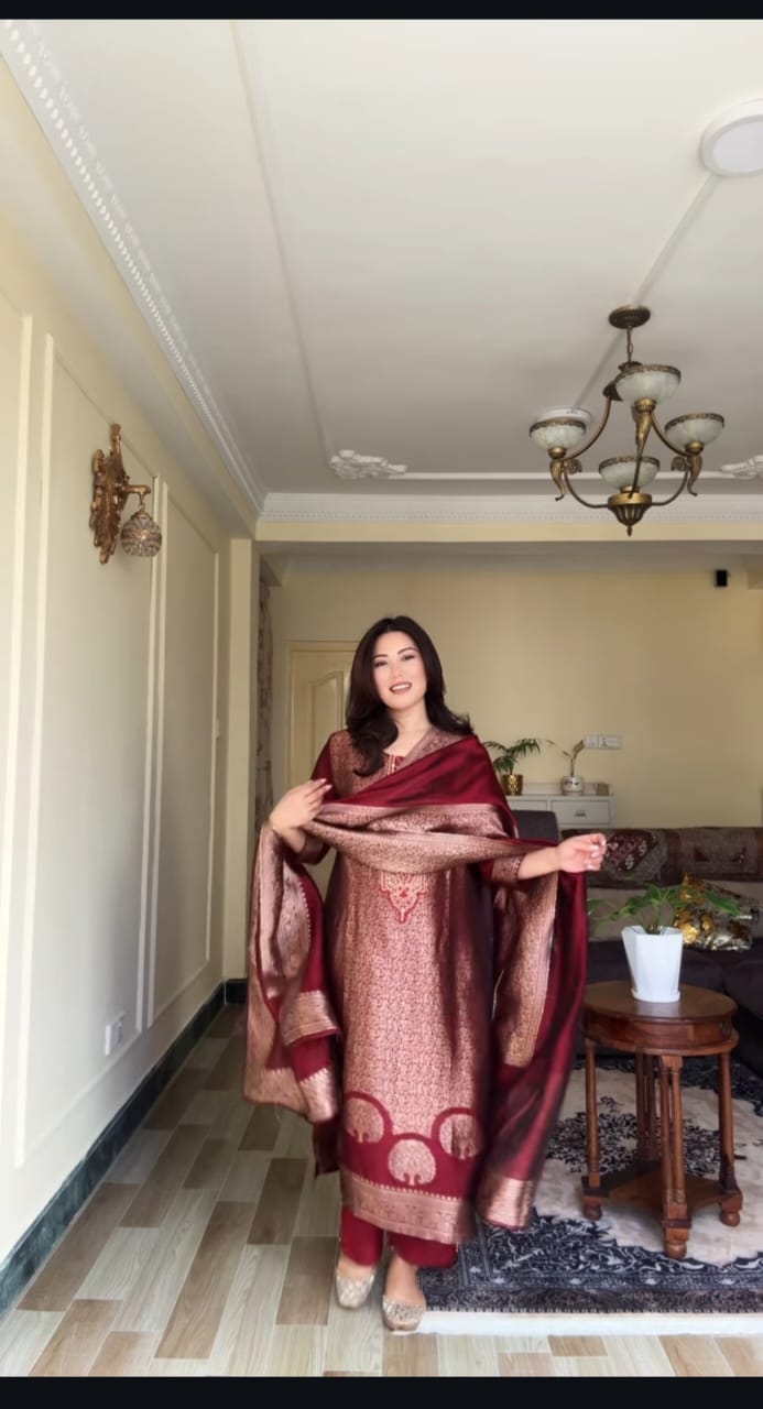 Model showcasing deep berry Banarasi suit set, holding dupatta elegantly.
