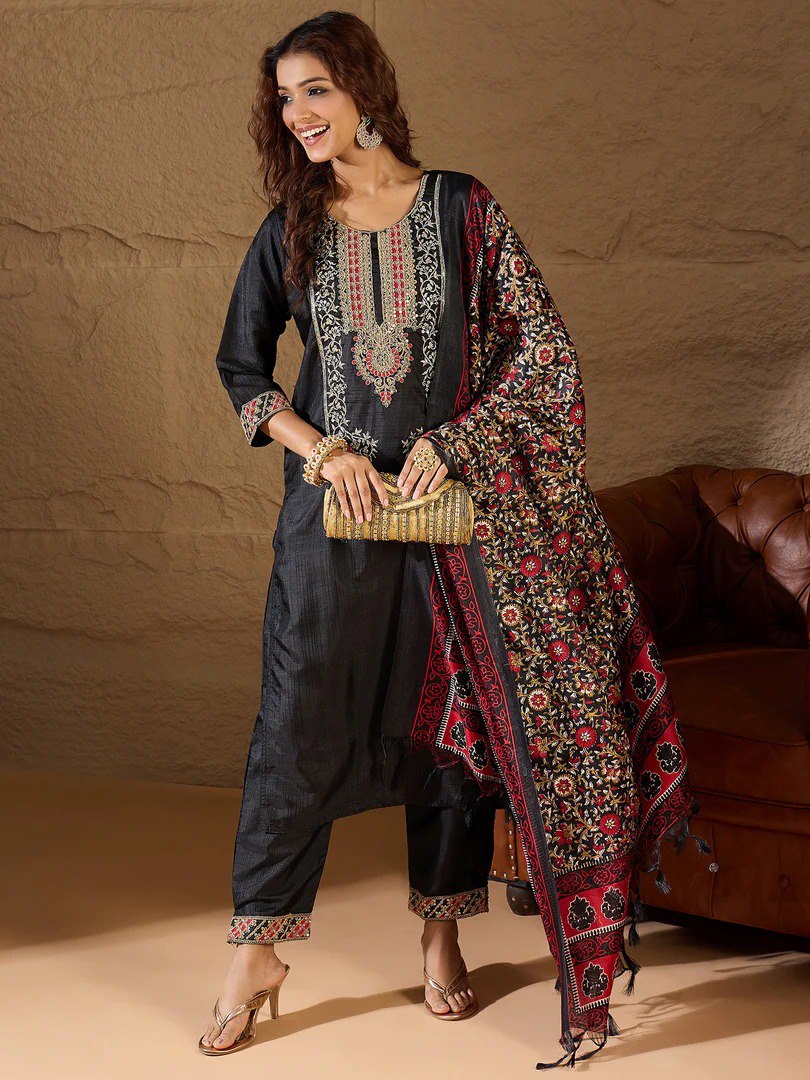 Woman in black cotton silk embroidered kurta set with red and black floral dupatta, holding a golden clutch.