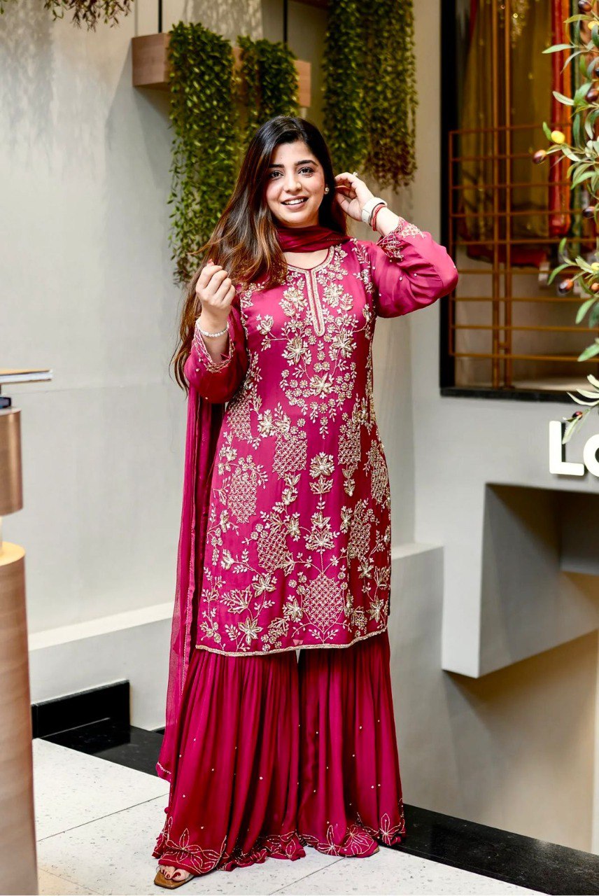 Woman smiling, wearing a magenta embroidered faux georgette plazzo suit with matching dupatta.