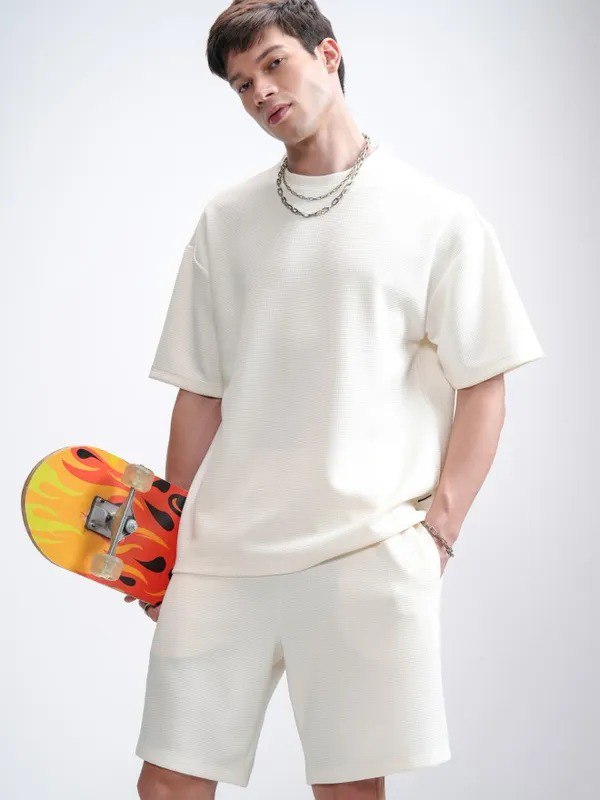 Man posing with skateboard wearing a cream mini waffle knit t-shirt and shorts co-ord set from TRENDBUY