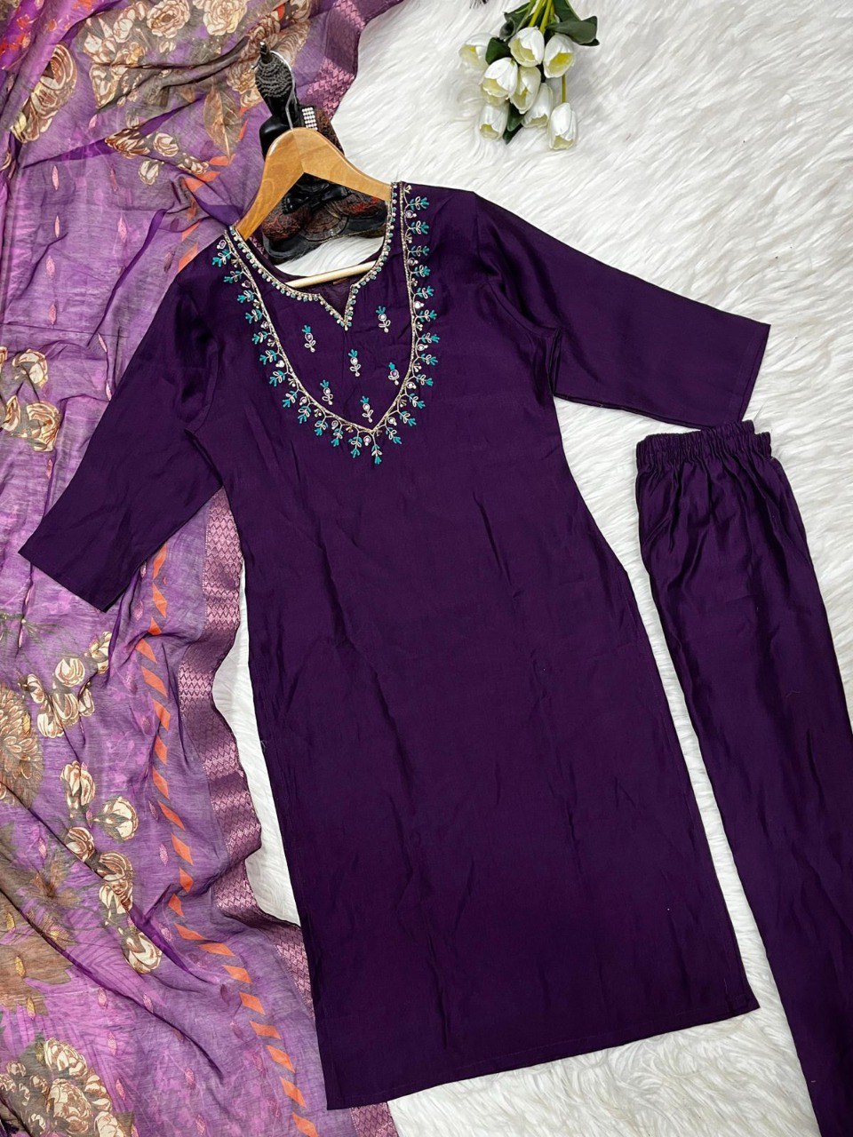 Flat lay of Plum Purple embroidered viscose kurti set with matching palazzo and jacquard dupatta on white fur.