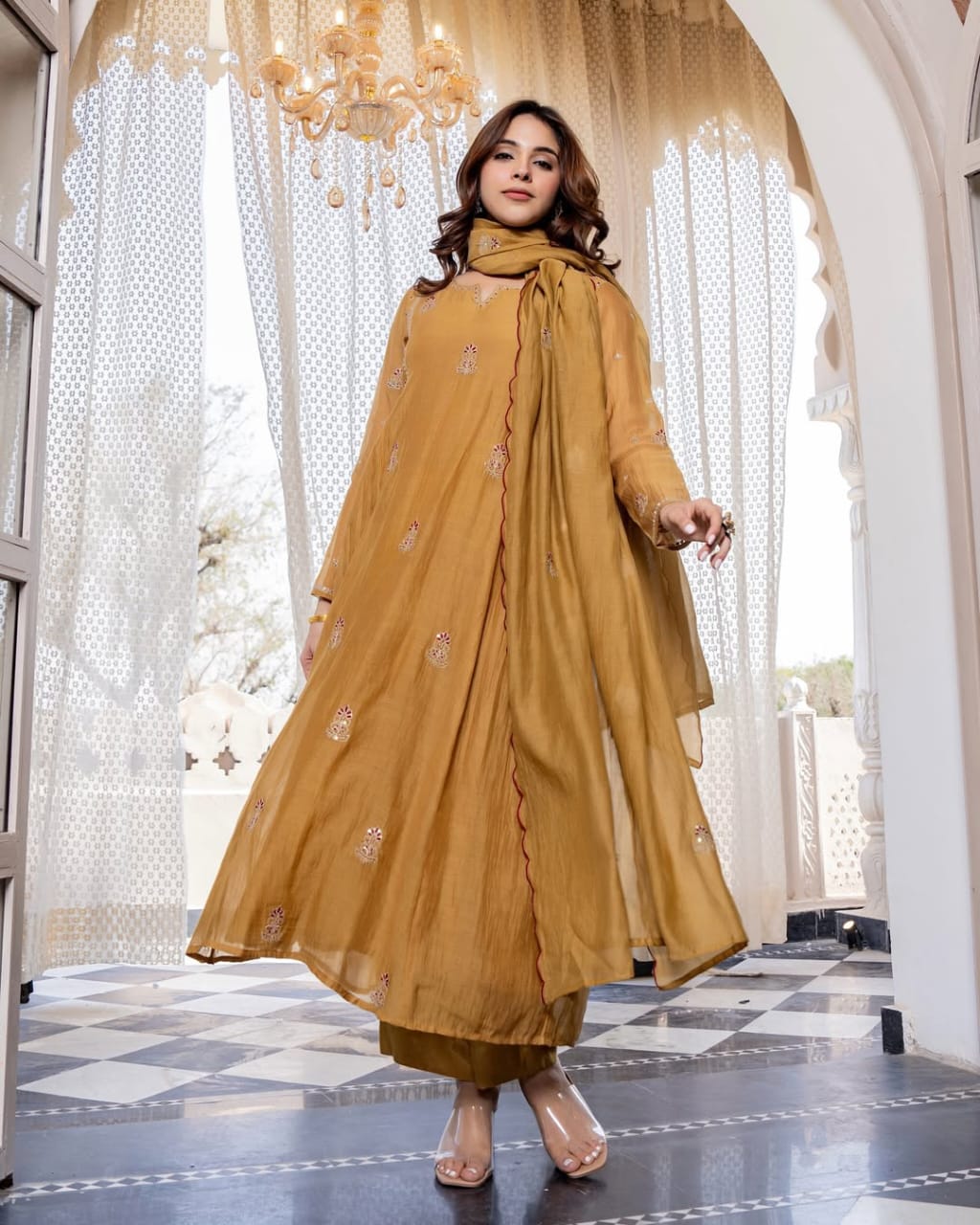 Model posing in a mustard gold Pankhudi Anarkali Chinon suit set with full embroidery, showcasing the flowing flare and elegance.