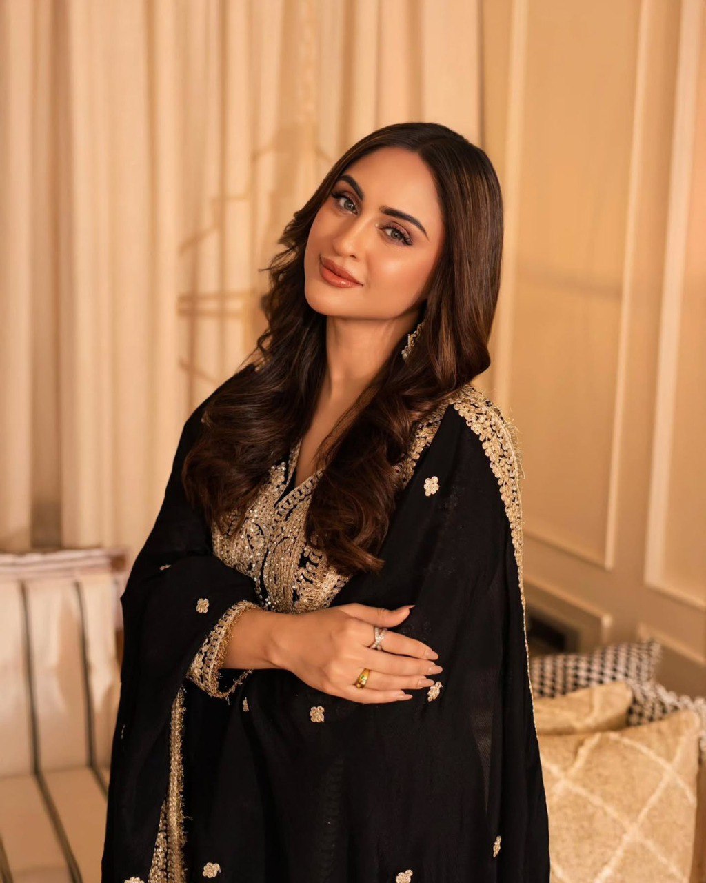Woman posing gracefully in black Georgette kurta set with gold embroidery