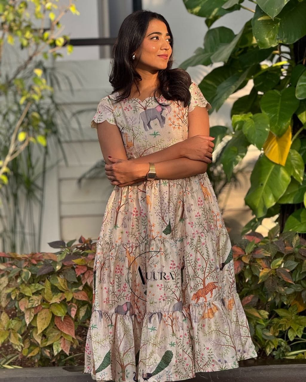 Woman standing outdoors wearing a light cream jungle print tiered maxi dress, facing sideways, highlighting the elegant fit and nature-inspired pattern.