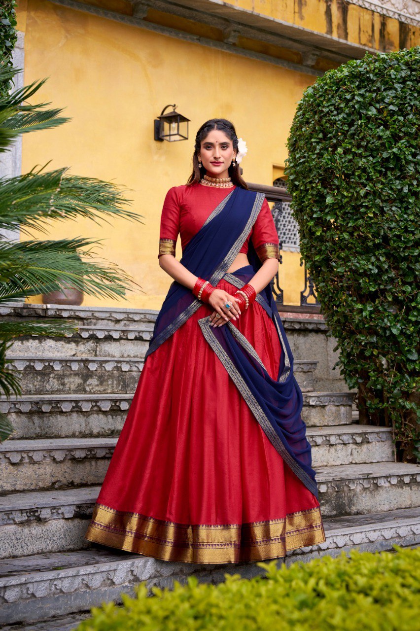 Model posing in a red poly cotton half saree lehenga with a navy blue georgette dupatta, featuring zari weaving work, standing on stone steps outdoors.