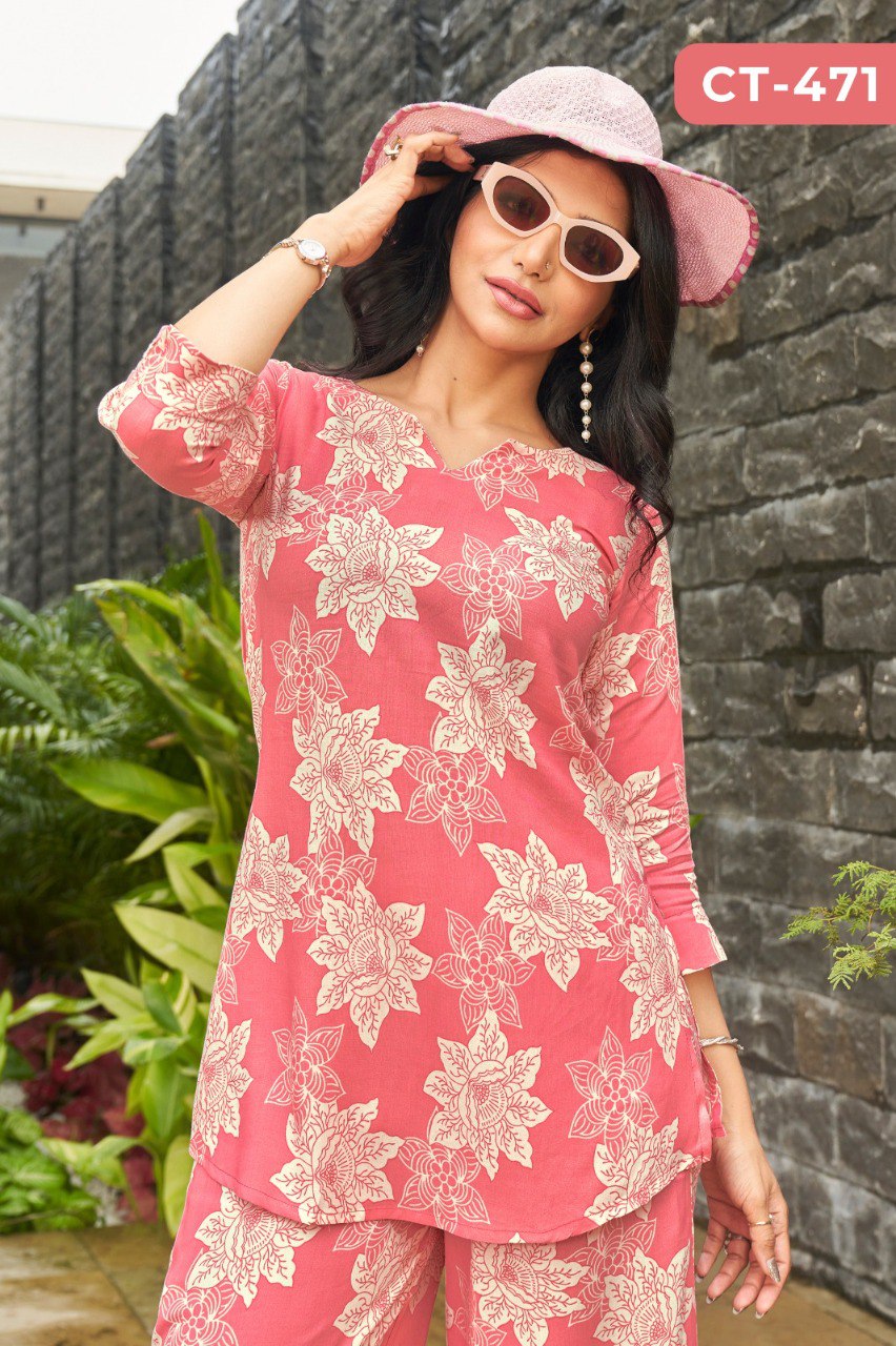 Woman wearing a coral pink rayon floral kurta and palazzo set, posing with a pink hat and sunglasses, showcasing the CT-471 design.