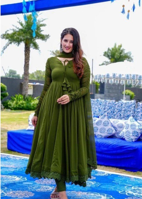Model showcasing the elegant fit of the TRENDBUY Olive Green Georgette Anarkali Gown with lace detail and matching dupatta, worn outdoors at an event.