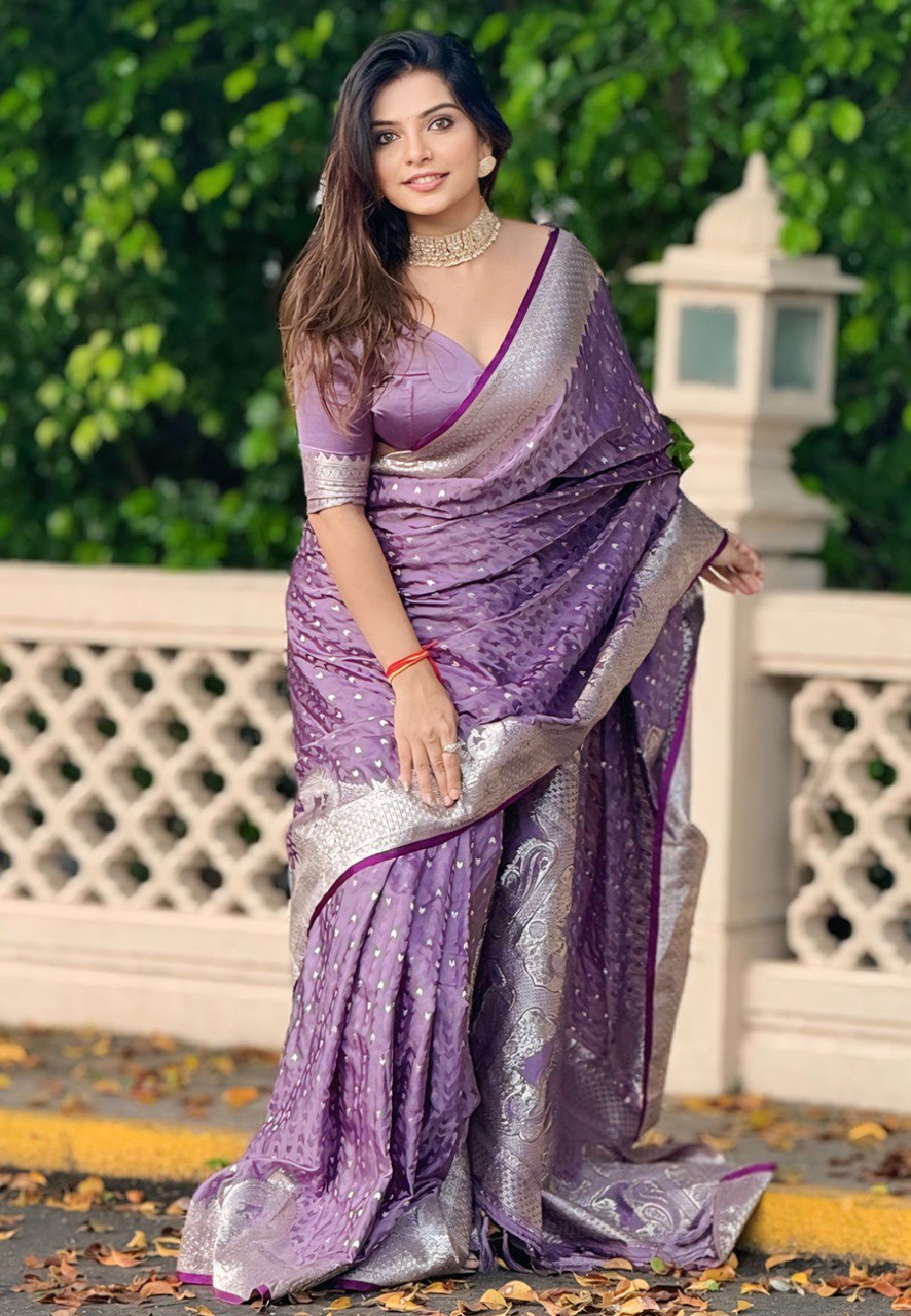 Lavender Banarasi Saree with silver zari and peacock pallu, worn by a smiling model.
