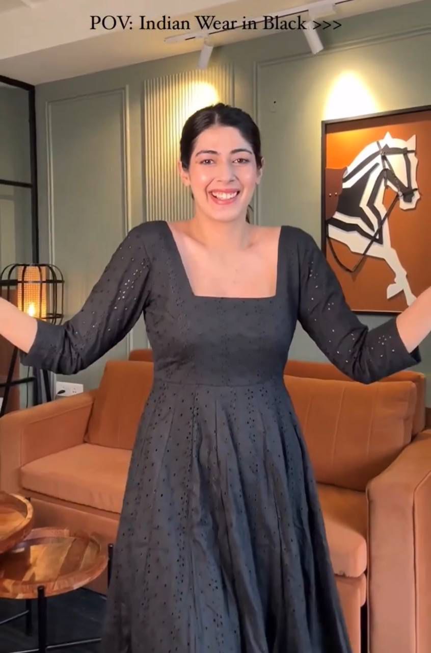 Woman happily posing in a full view of black Hakoba Anarkali suit, showcasing the dress's elegance and detailed schifli work.