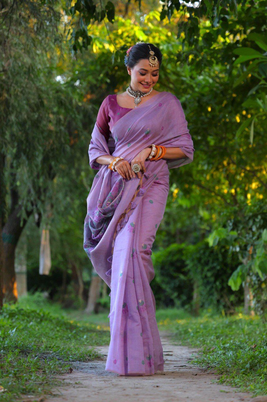 TRENDBUY model in lavender Muga cotton saree with all-over floral weaving and elegant jewelry, standing in a lush garden.