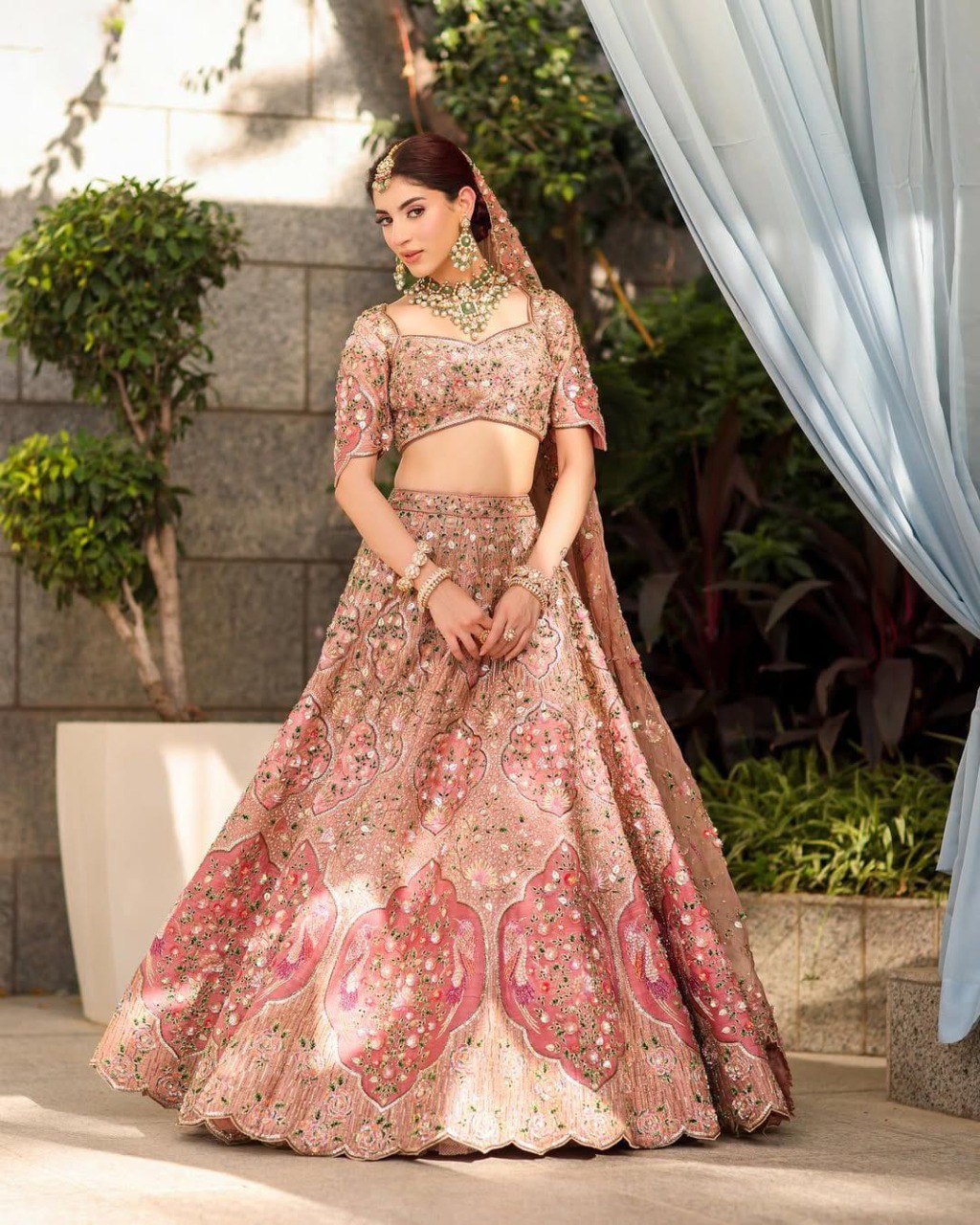 Full shot of model in blush pink slub silk lehenga with heavy embroidery and traditional jewelry.
