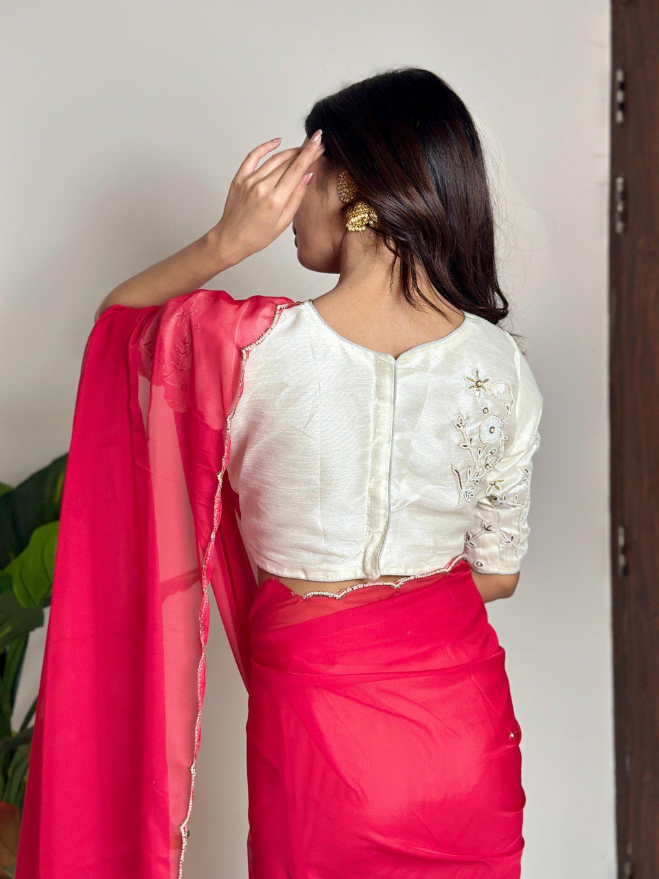 Model from back, wearing a vibrant rani pink soft organza saree with a pearl cutwork border and an embroidered white satin blouse.