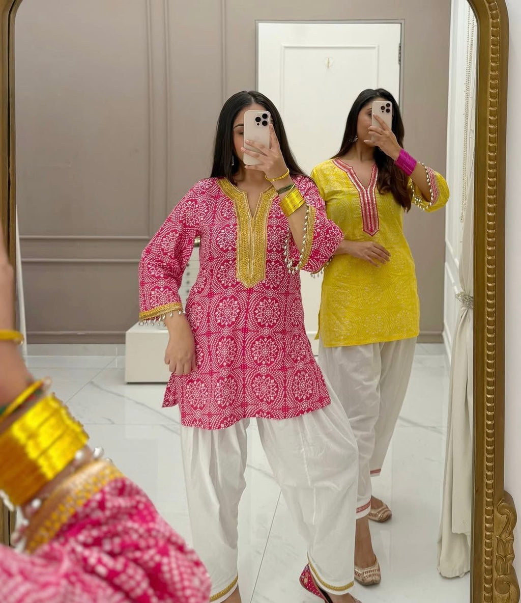 Two models showcasing pink and yellow French crepe salwar suits with mirror reflection.
