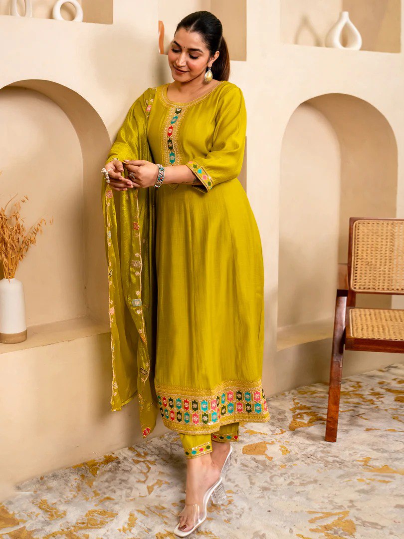 Woman wearing a lime green soft silk Anarkali kurta set with embroidered details, standing gracefully against a neutral background.