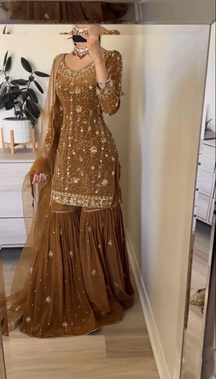 Model in elegant bronze georgette sharara suit with zarkan work, full view in mirror.